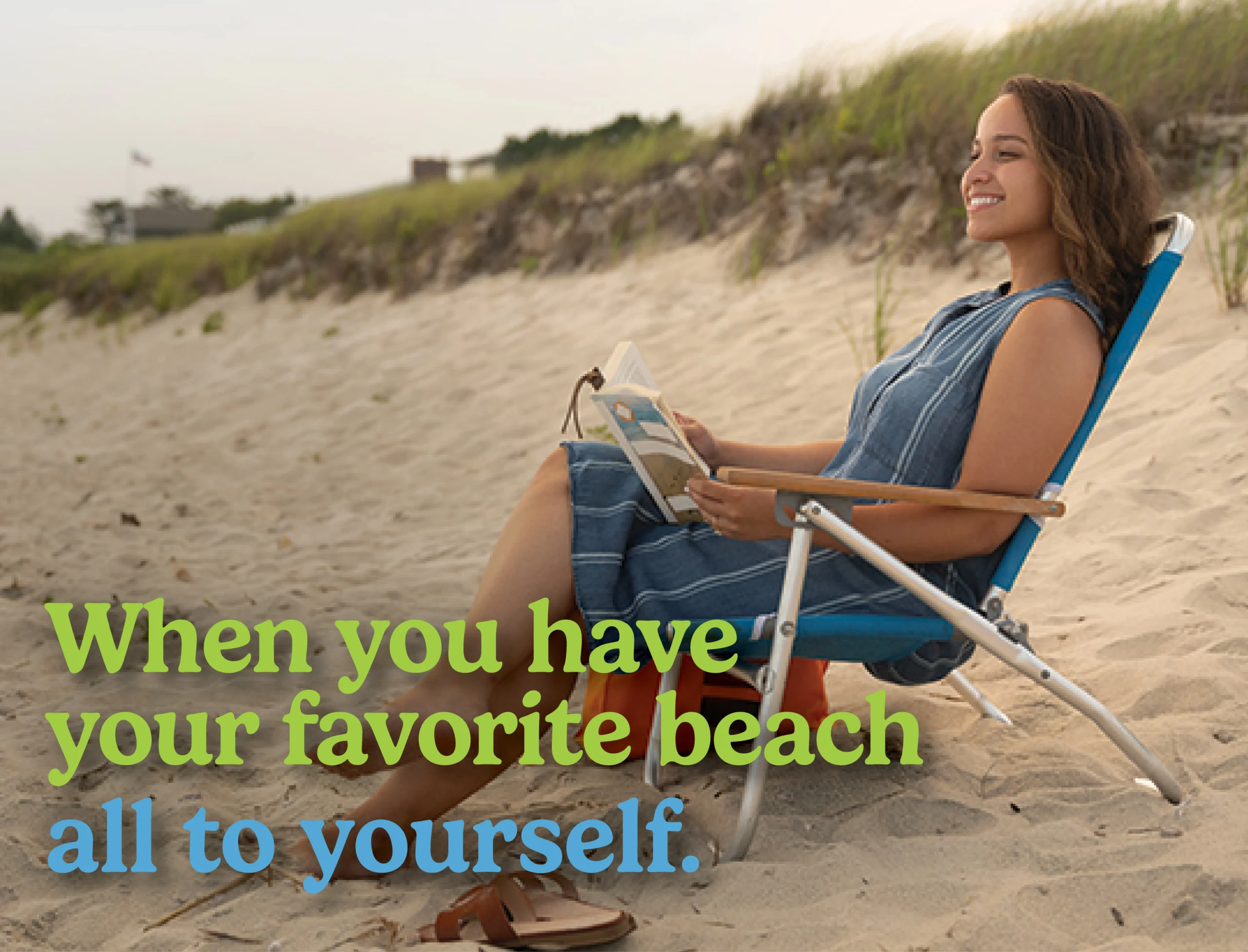 Woman sitting in beach chair with book in hand enjoying an empty beach