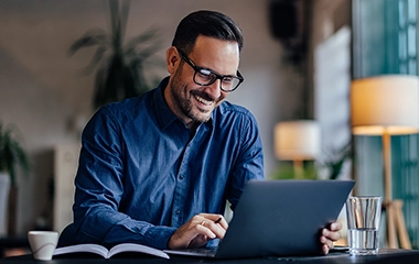 A man smiling looking at his laptop