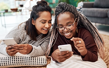 Two women smiling on their phones