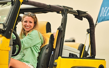 A woman driving a yellow jeep