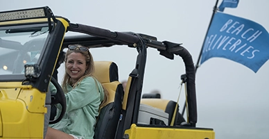 A woman driving a yellow jeep