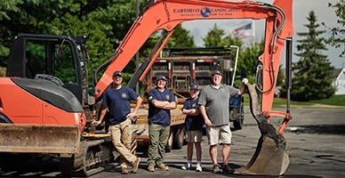 Earthday Landscaping family team pose in front of heavy equipment.
