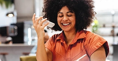 African American woman smiling and talking on iphone on speaker while taking notes