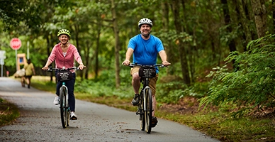 Adult male and female bike together on the Cape Cod Rail Trail.