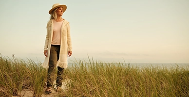 Older woman standing on the dunes of a Harwich beach at golden hour, looking off to the horizon