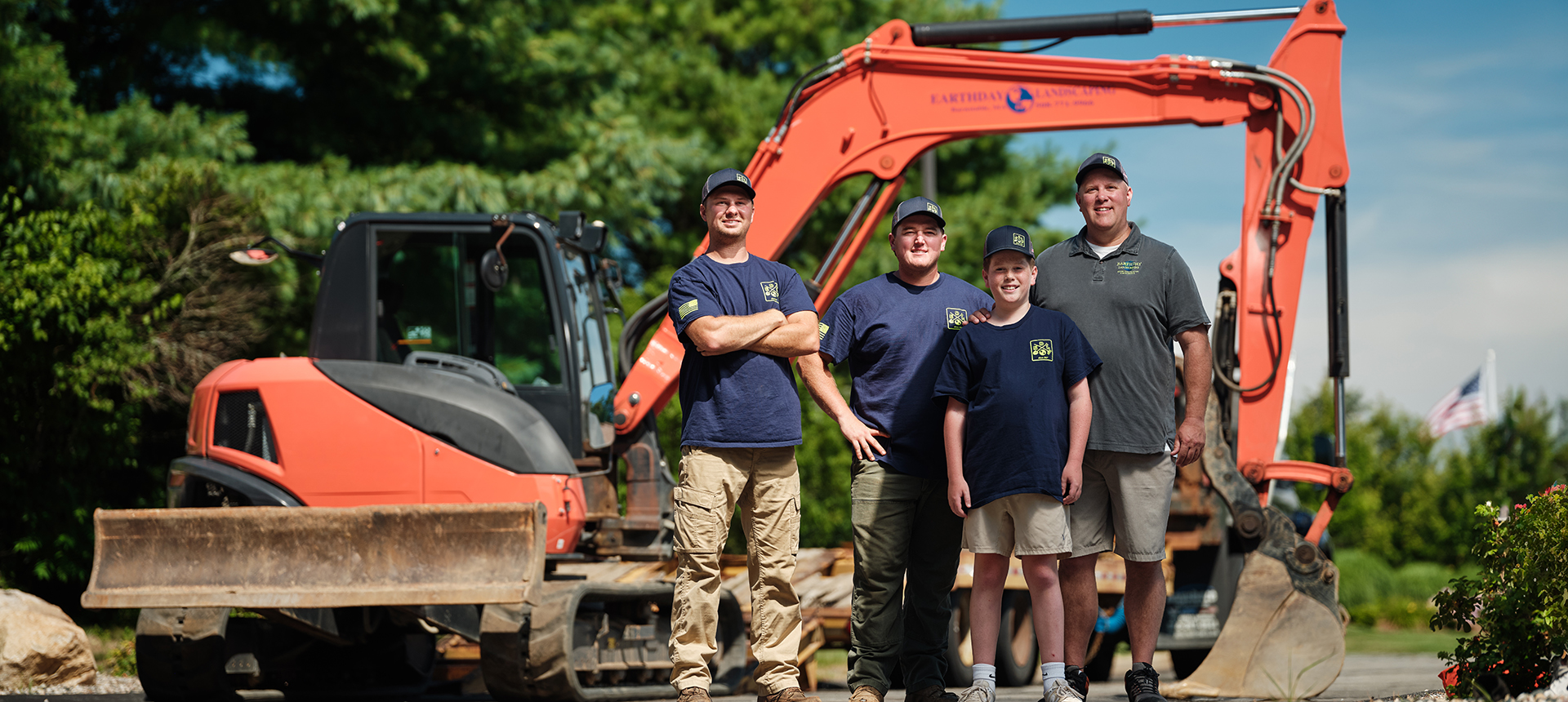 The team at Earth Day Landscaping poses in front of hardscape equipment.