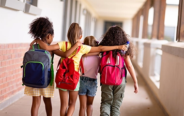 Four kids walking a school hallway with backpacks