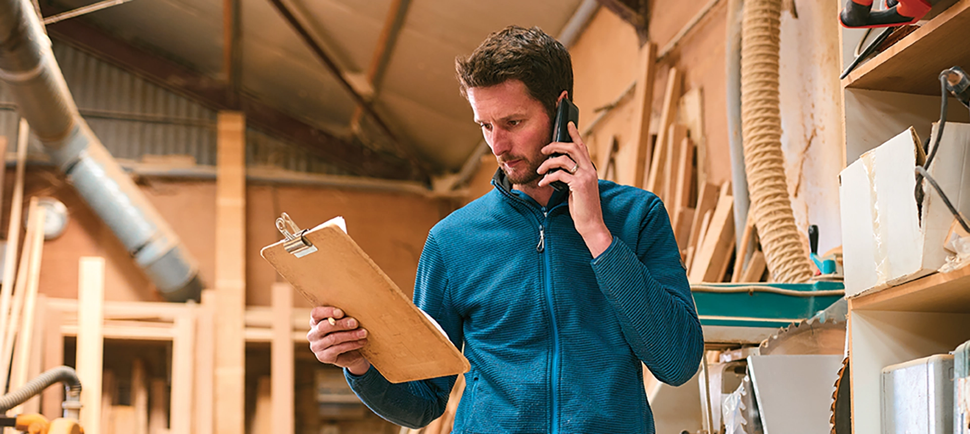 A worker on the phone and looking at a clipboard