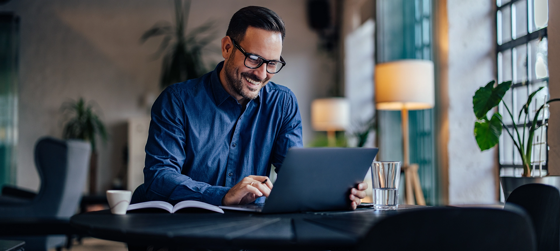A man smiling and looking at his laptop