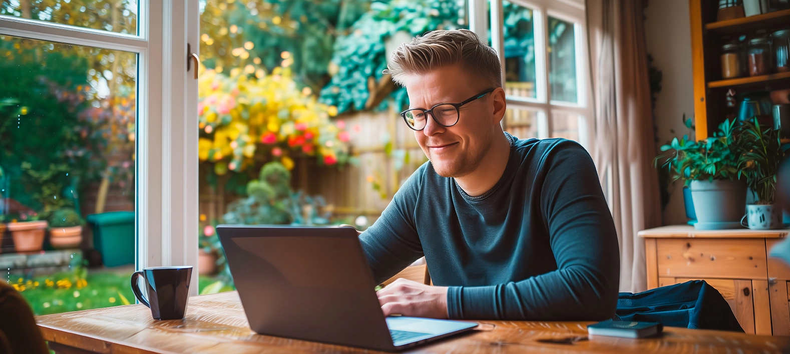 A man smiling and looking at his laptop