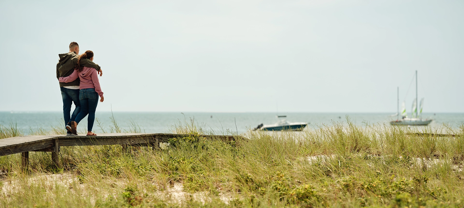 A couple walking down a dock to the ocean