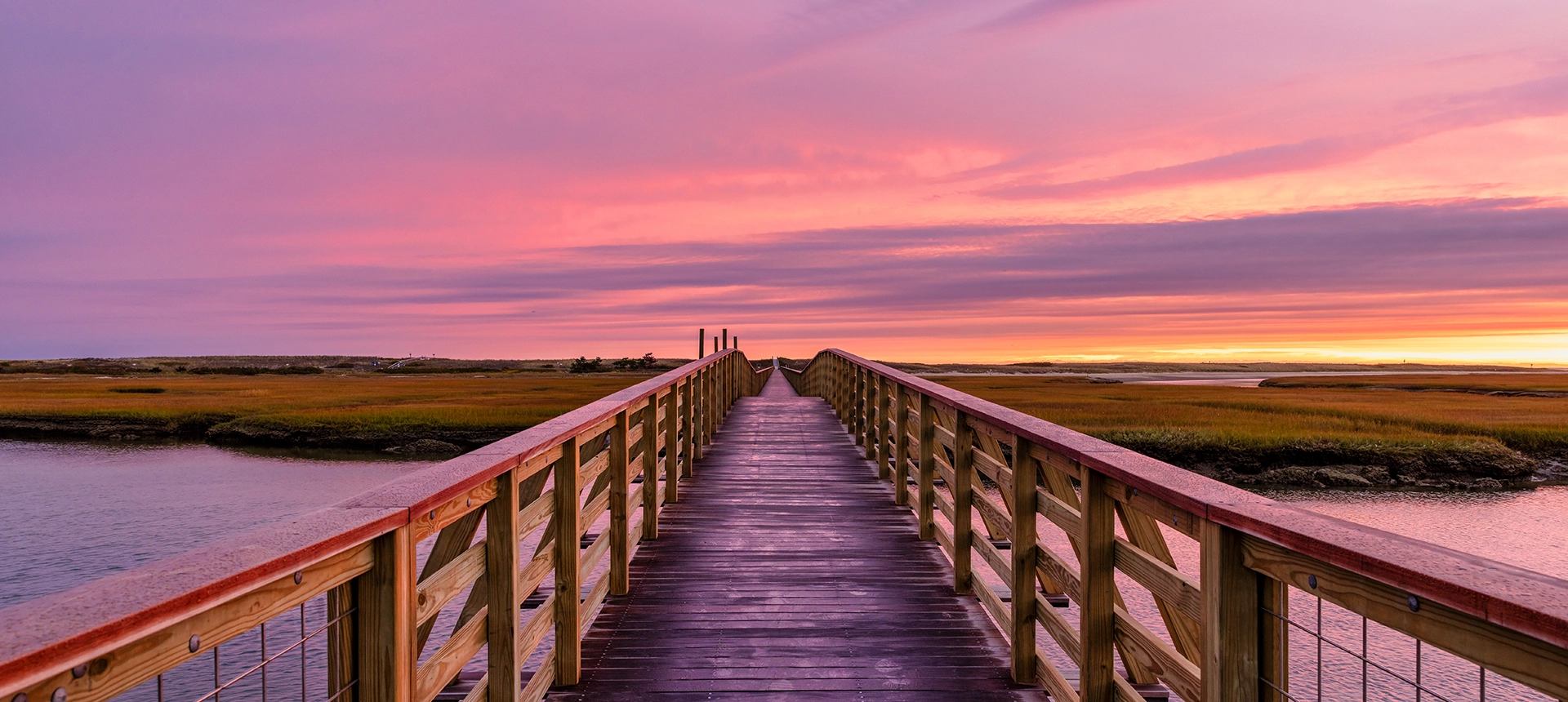 A dock at the beach during sunset