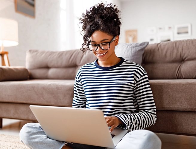 A woman smiling and looking at her laptop
