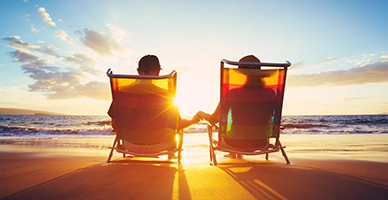 Back view of a couple sitting in beach chairs looking at tide surf during golden hour