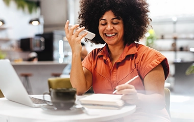 A woman smiling on her phone and taking notes