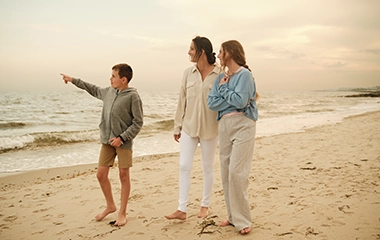 Mother, child son, and teenage daughter enjoy a golden hour walk on a Harwich beach.