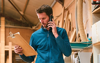 A store owner on the phone and looking at a clipboard
