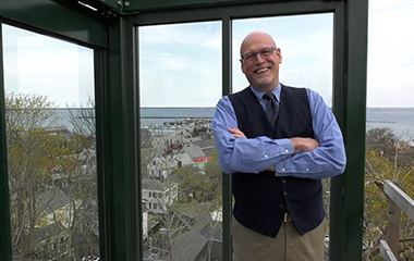 A man standing in a glass box with his arms crossed