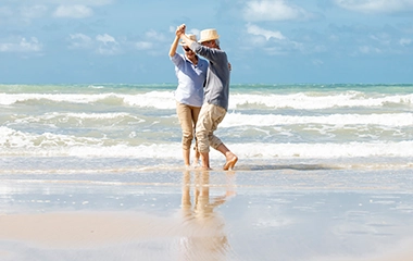 Retirement age couple dance together on the beach