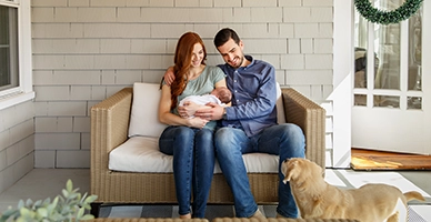 new parents hold their newborn baby at home, introduction to family dog