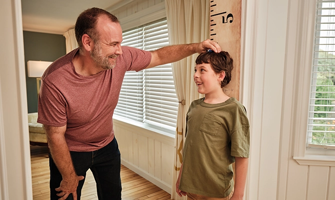 A father measuring his sons height on the wall