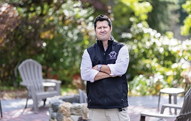 A property manager crossing his arms in front of a fire pit