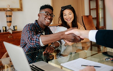 A couple shaking hands with a real estate lender