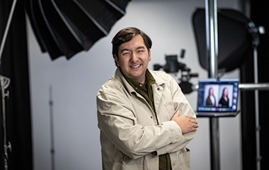 A man crossing his arms with camera equipment in the background