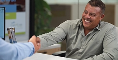 Man shaking bank representative's hand, sitting at bankers desk.